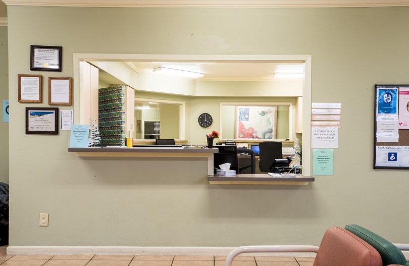 Patients sit in a bright community clinic waiting room before their appointments.